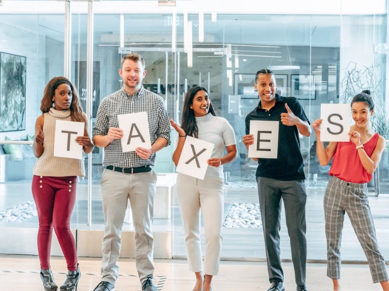 People are standing in a line with TAXES boards in hand
